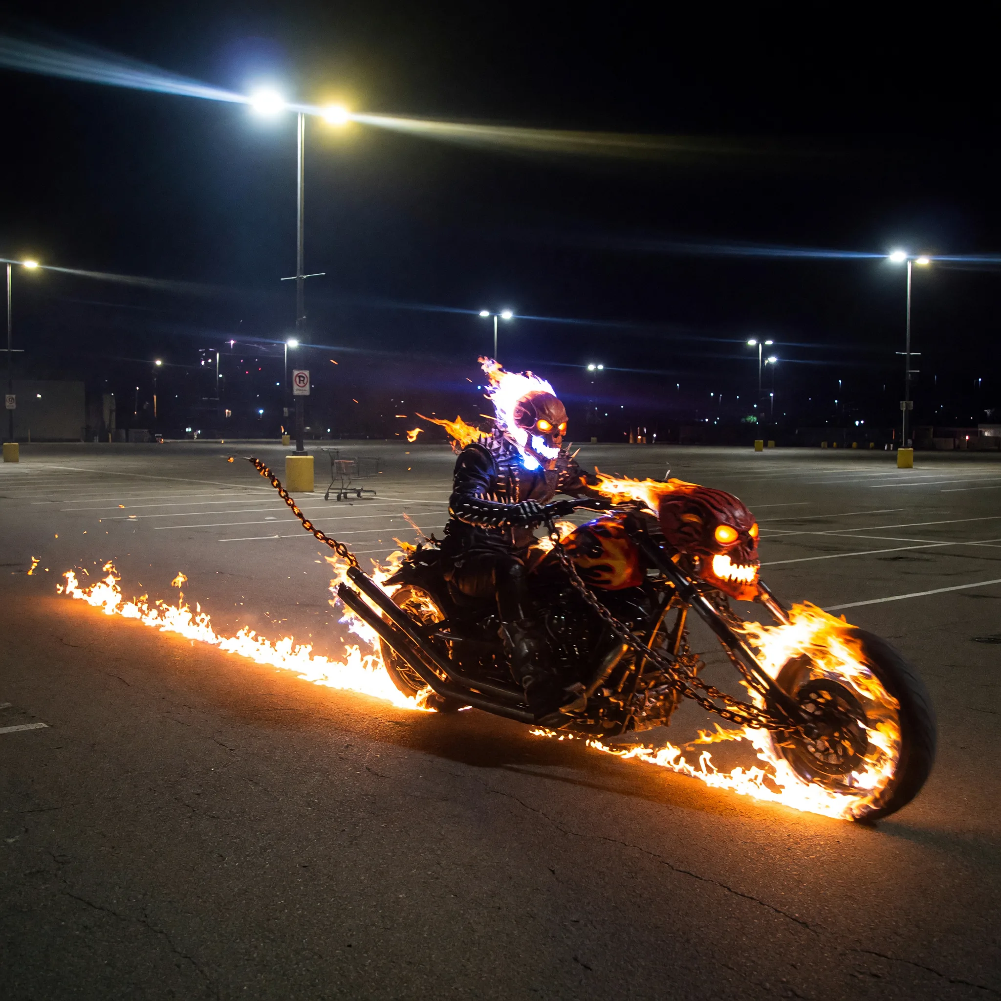 Grok Image prompt: Ghostrider's stretched flaming skull and chains motorcycle in an empty parking lot at night driving very fast leaving fiery trail.