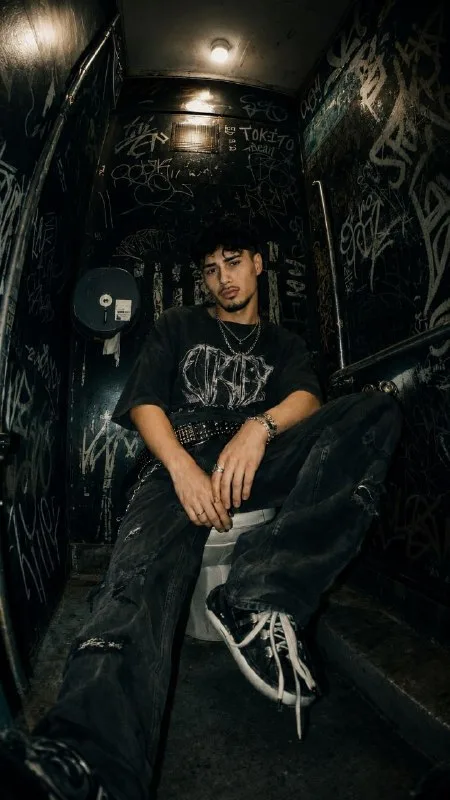 Ultra-realistic underground fashion editorial photo of the SAME PERSON from the reference image inside a cramped