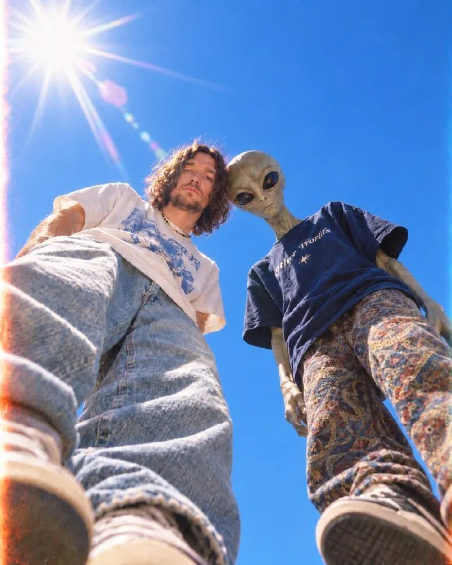 An extreme worm's-eye-view photograph shot from ground level looking straight up: a man with the face