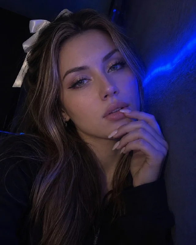 SHOT — Photorealistic night selfie portrait, close frame with a slight Dutch tilt; a young woman